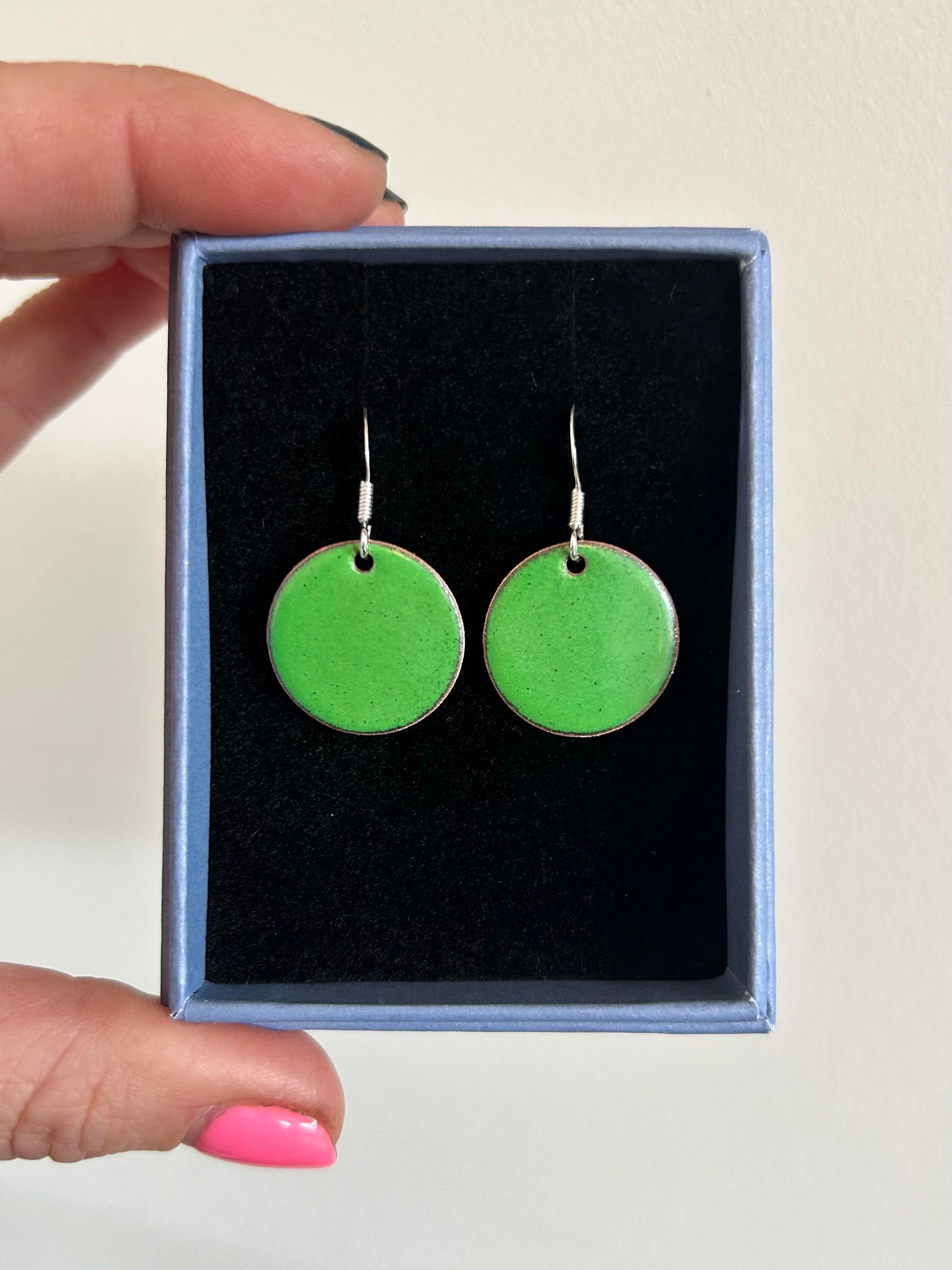 A pair of 20mm green enamel disc earrings in a box.