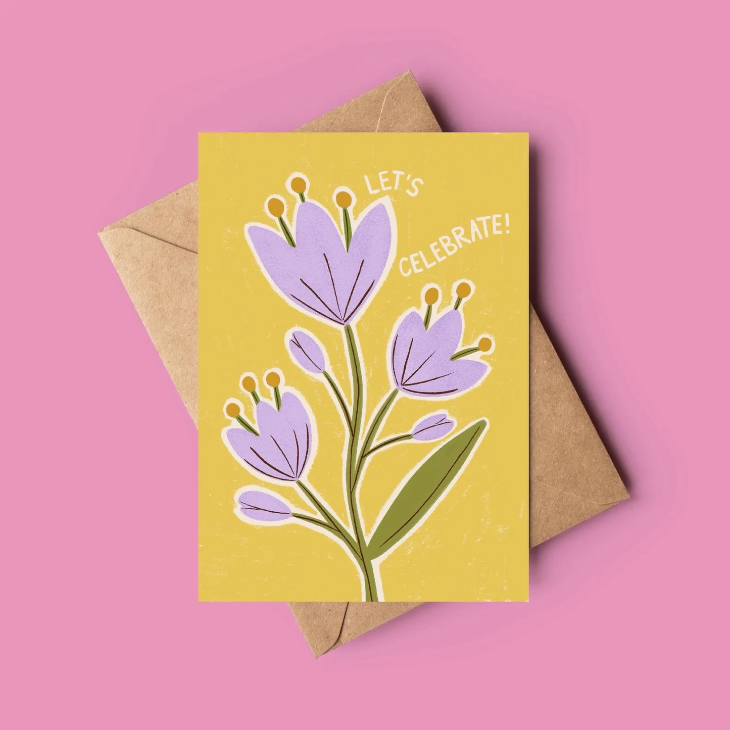 Greeting card with purple flowers and 'Let's Celebrate!' text on a yellow background, with a brown envelope.