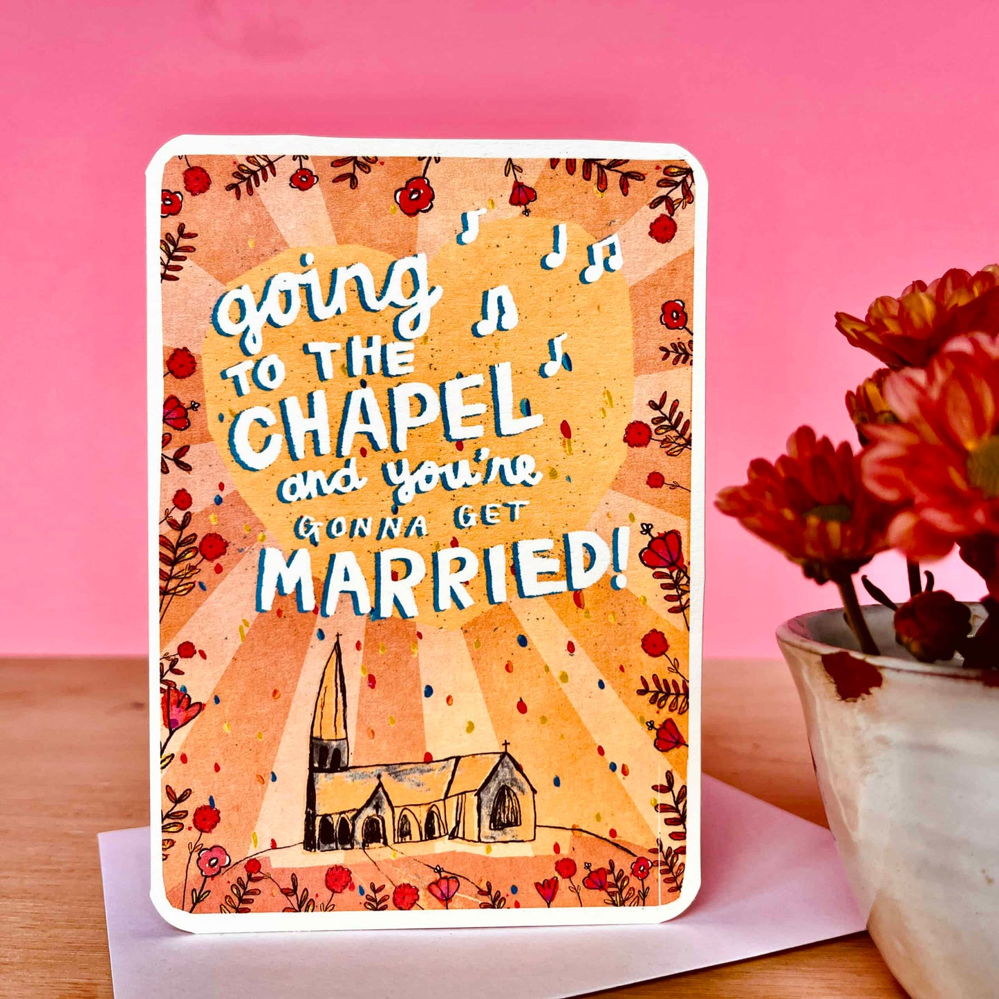 Wedding card with chapel illustration and text 'going to the chapel and you're gonna get married!' on a pink background.