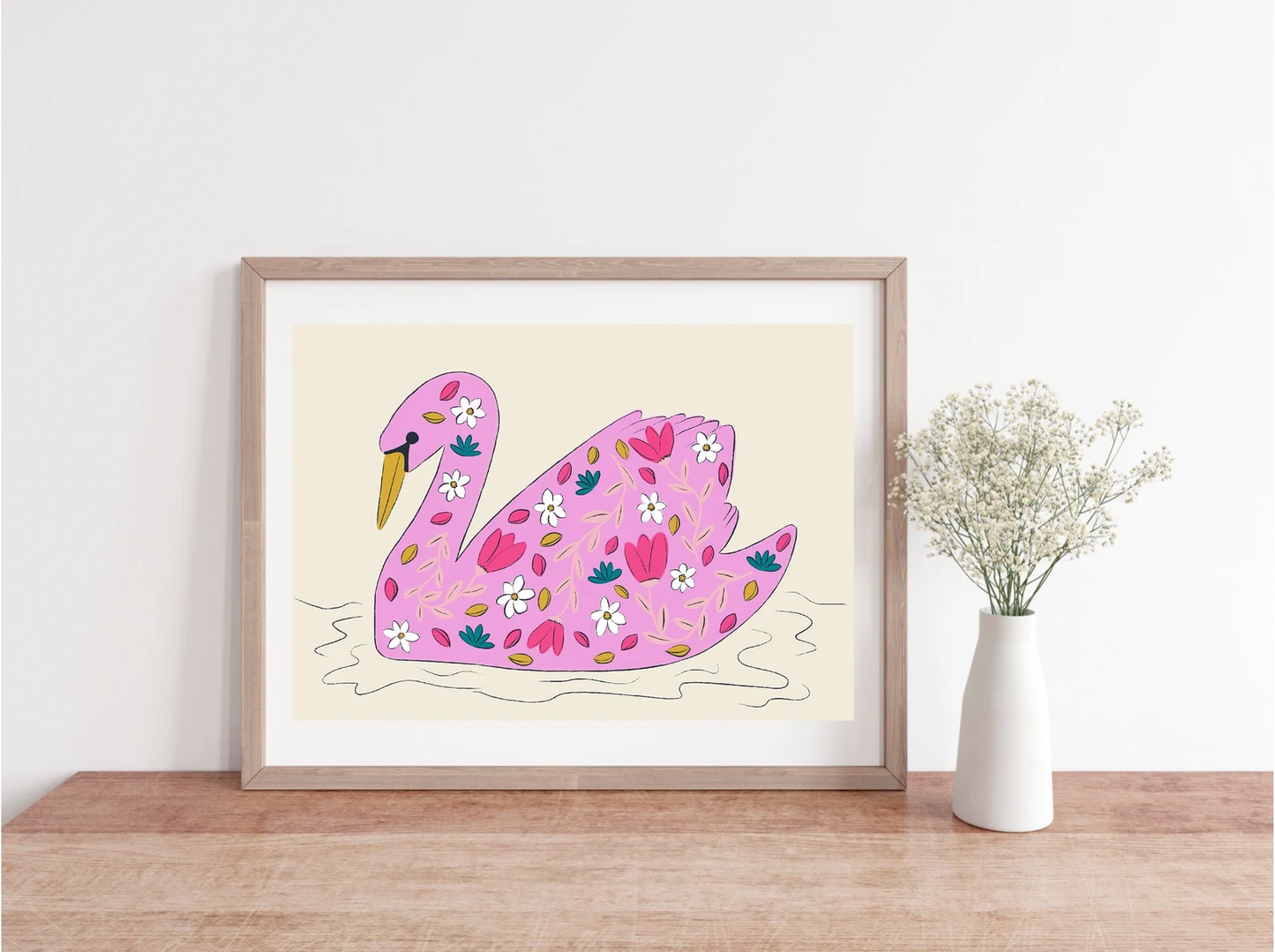 Framed artwork of a pink swan with floral patterns on a white wall.