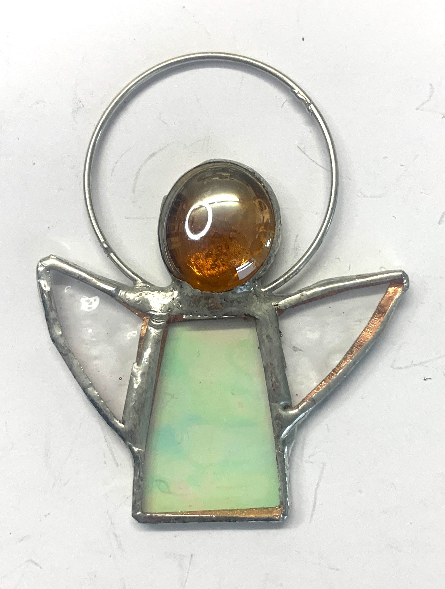 Stained Glass Angels. Individually made by hand. Many colour choices and variations. A choice of a clear or amber nugget head. The glass texture may vary slightly from the photographs. The clear glass wings will vary in texture too. Size 5cm x 7cm including halo. Glass is cut to shape and copperfoiled, followed by soldering all the pieces together. Handmade by Dadswell Glass at Glass Designs in Bristol.