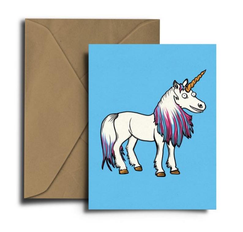 Glass Designs Dixon Does Doodles card with a smiley unicorn on a blue background