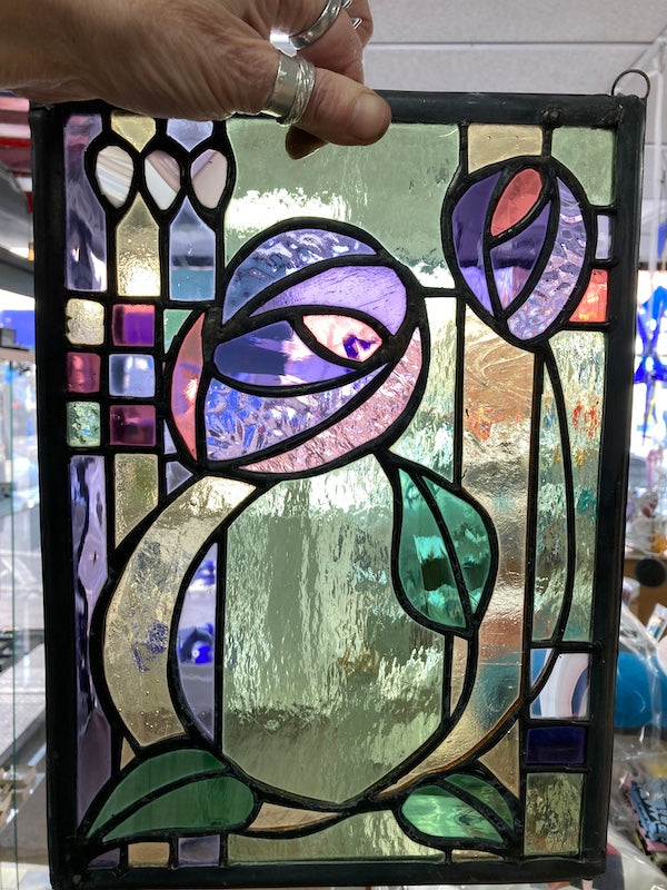 A Charles Rennie Mackintosh inspired stained glass hanging, with roses and leaves over a geometric design. Handmade by Dadswell Glass at Glass Designs in Bristol.
