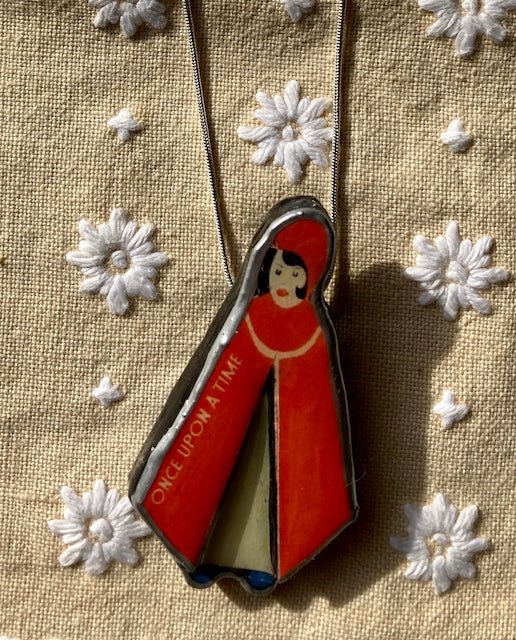 Handmade in Cardiff by layering paper, metal and resin. This pendant is of Little Red Riding Hood with the words Once upon a time on her cape.