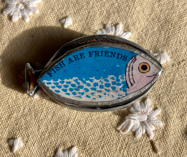 Fish are Friends blue fish brooch, made by layering paper, metal and resin. Handmade in Cardiff.