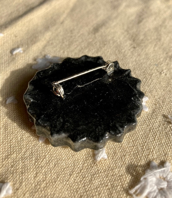 This George Orwell Eye brooch is handmade by Elemental a Cardiff artist. Made from layered paper and metal a laquered with resin to seal. The text around the eye reads It was a bright cold day in April and the clocks were striking the thirteen.