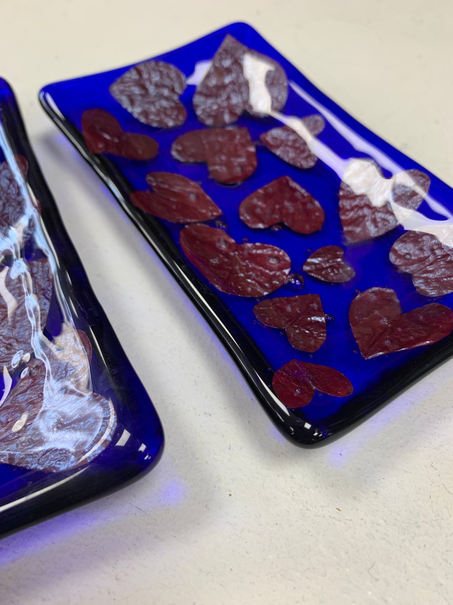 Bristol Blue Glass fused trinket dish or soap dish with Rusty red hearts fused between the glass. Handmade in Bristol.