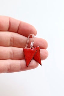 A pair of red inverse triangle earrings. The earrings are suspended from small silver hooks.