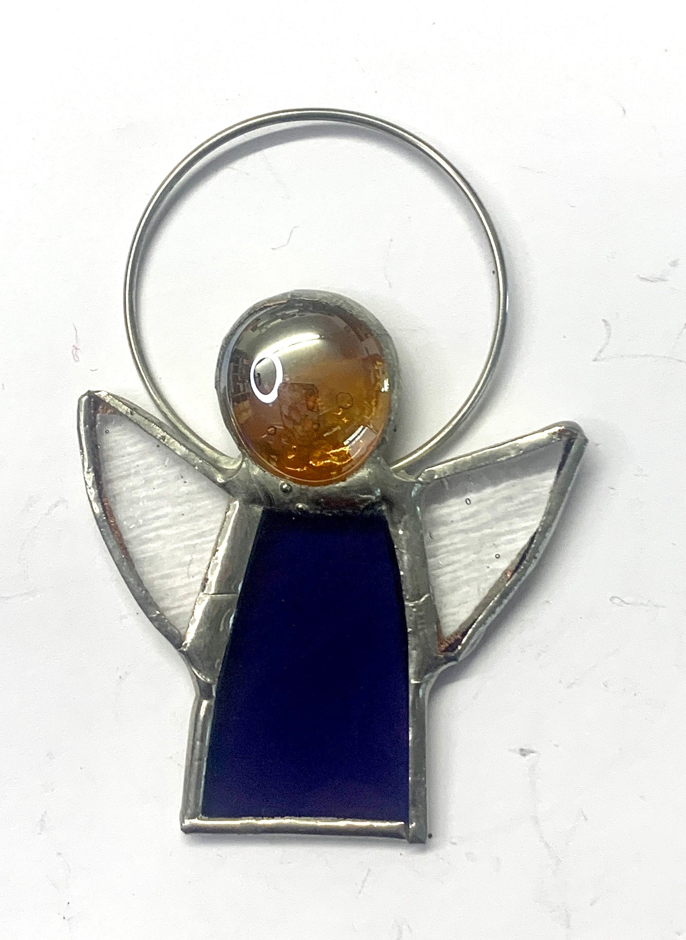 Stained Glass Angels. Individually made by hand. Many colour choices and variations. A choice of a clear or amber nugget head. The glass texture may vary slightly from the photographs. The clear glass wings will vary in texture too. Size 5cm x 7cm including halo. Glass is cut to shape and copperfoiled, followed by soldering all the pieces together. Handmade by Dadswell Glass at Glass Designs in Bristol.