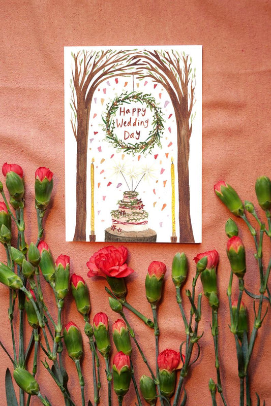 watercolour greetings card with cake, big candles, trees and a wreath with the words ''happy wedding day'' in
