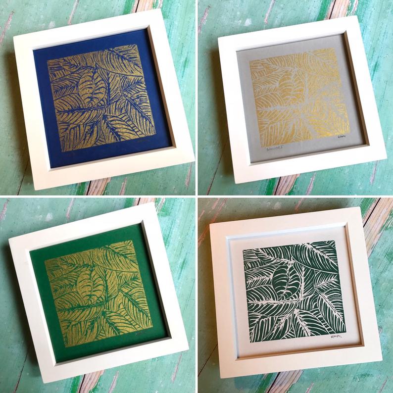 Trelawney Designs hand cut lino print with water based ink. Botanical leaves in Gold on a Dark blue back ground. Framed in a white frame.