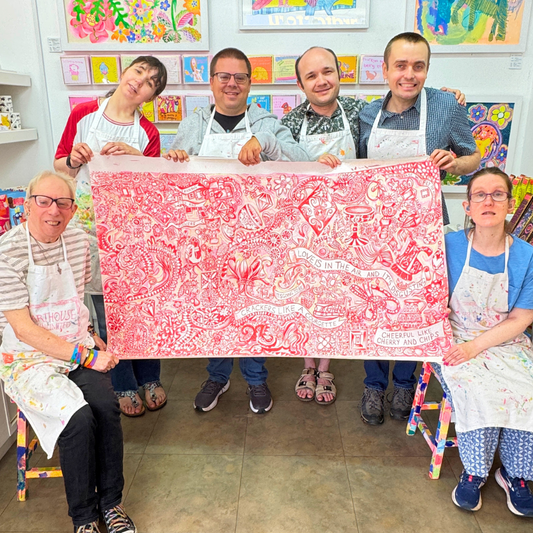 Group of people holding a large red and white patterned fabric in an art studio.