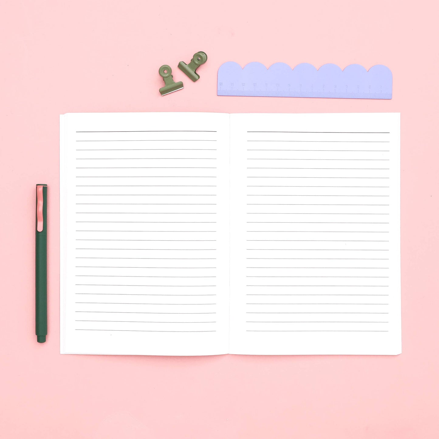 Lined notepad with a pen on a pink background