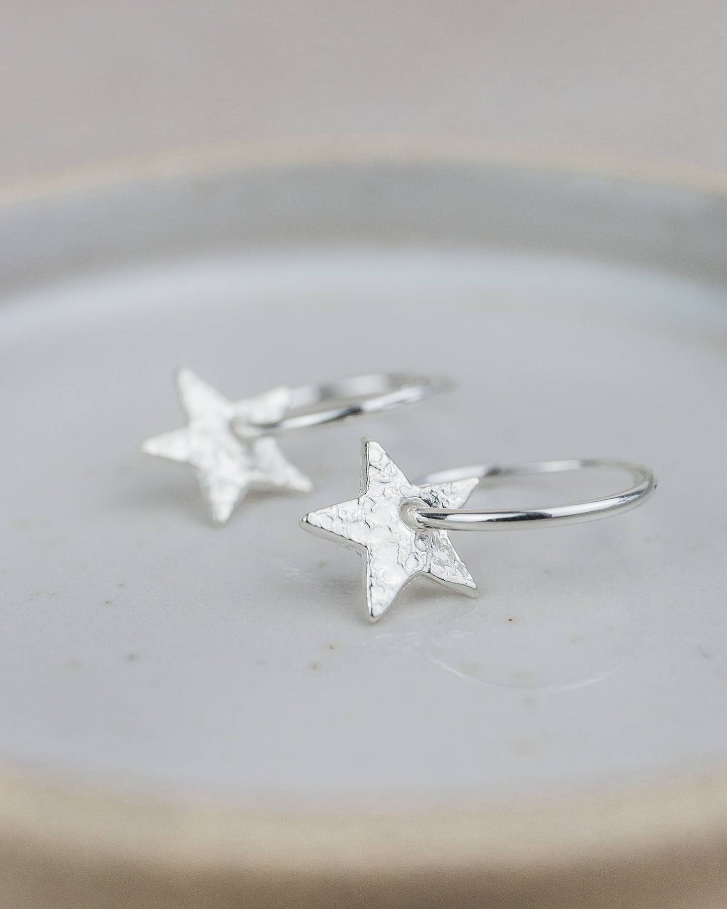Silver star earrings on a light gray surface