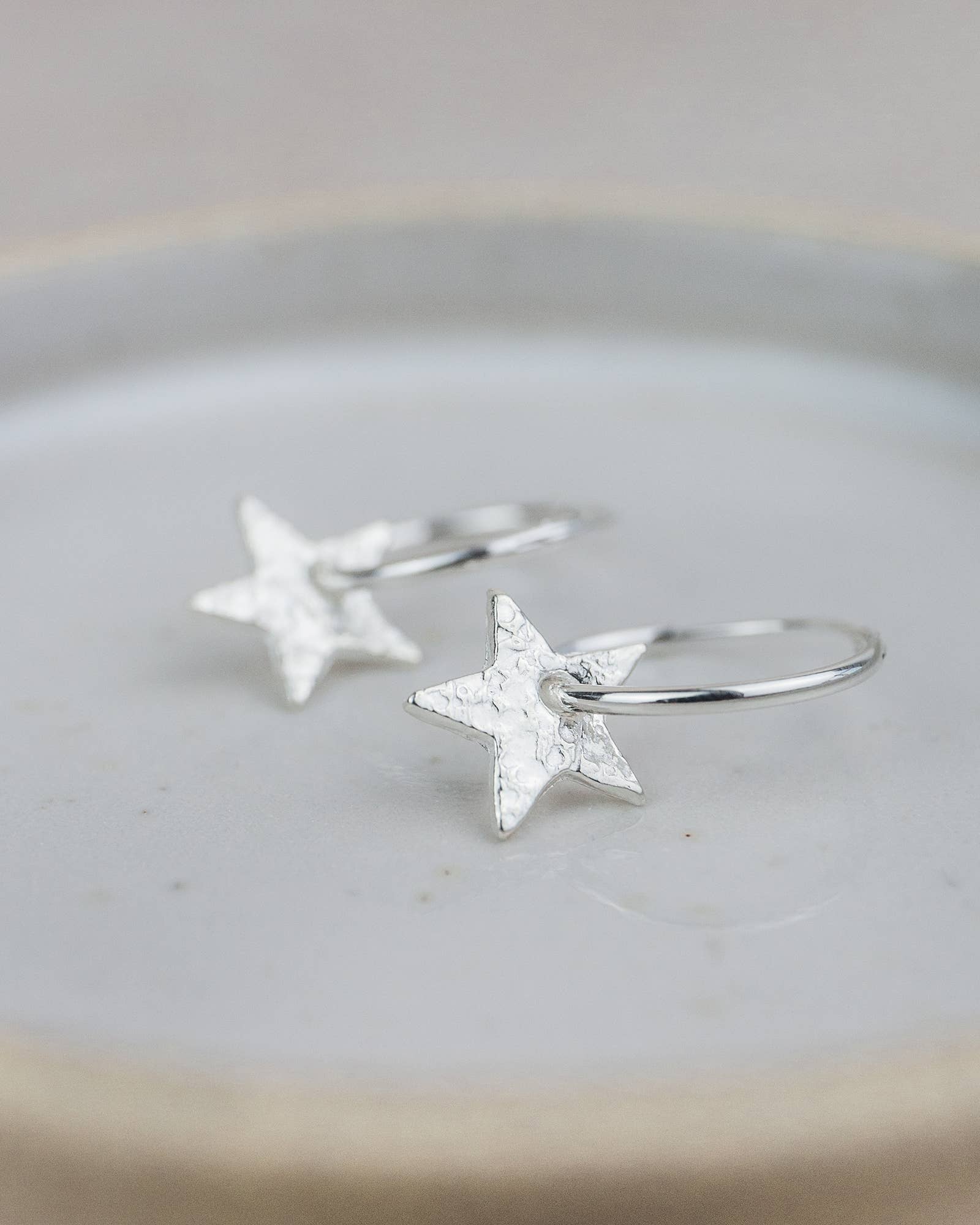 Silver star earrings on a light gray surface