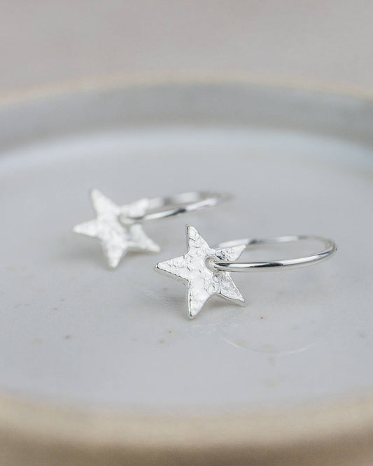 Silver star earrings on a light gray surface