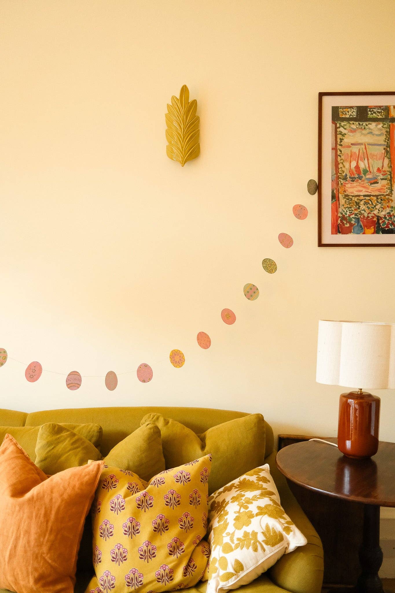 Living room with a green sofa, decorative pillows, and wall art.