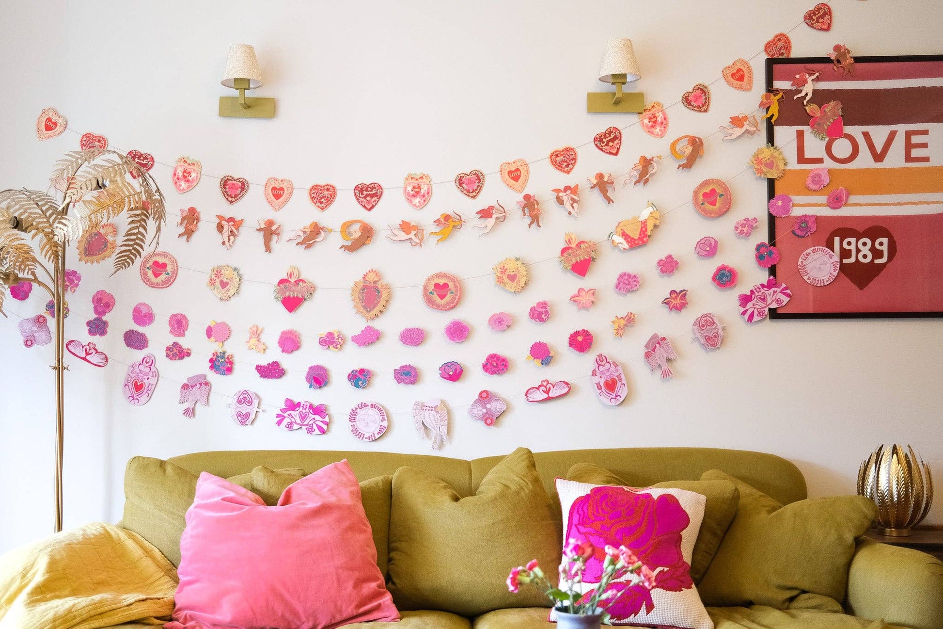 Living room with decorative wall stickers, a green sofa, and pink pillows.