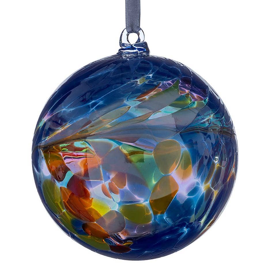 A hand-blown glass Christmas ornament in deep blue with colorful swirls of green, orange, yellow, and purple, hanging from a gray ribbon on a white background.