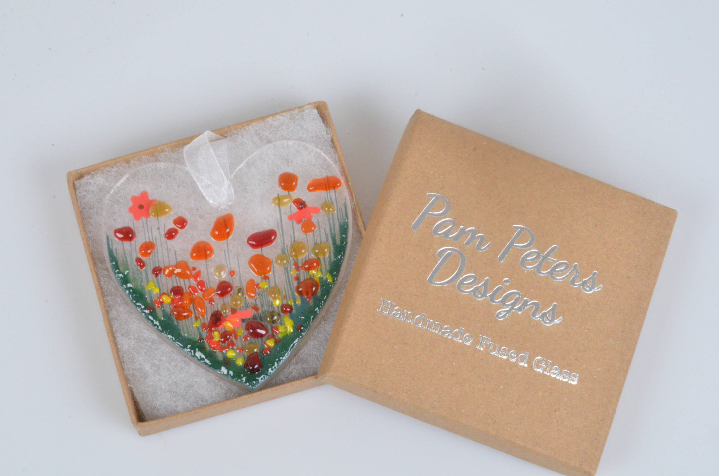 Heart-shaped glass artwork with colorful design in a box labeled 'Pam Peters Designs'.
