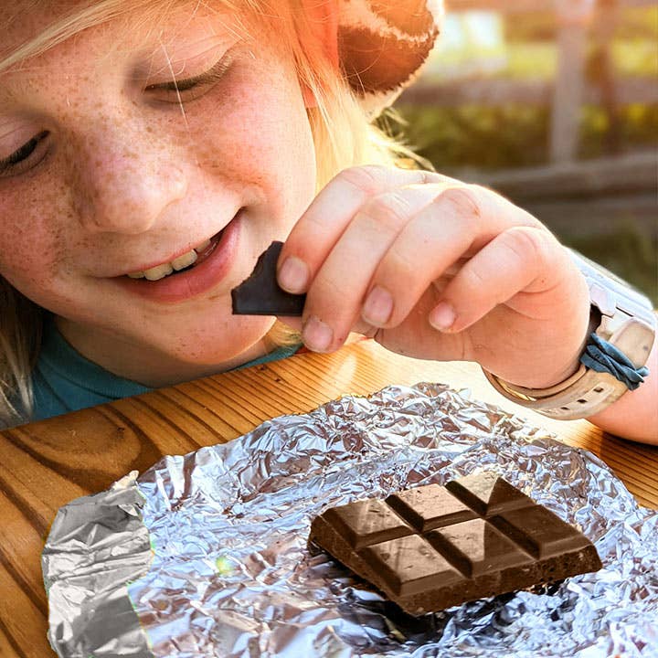 Child eating a chocolate bar outdoors on a sunny day
