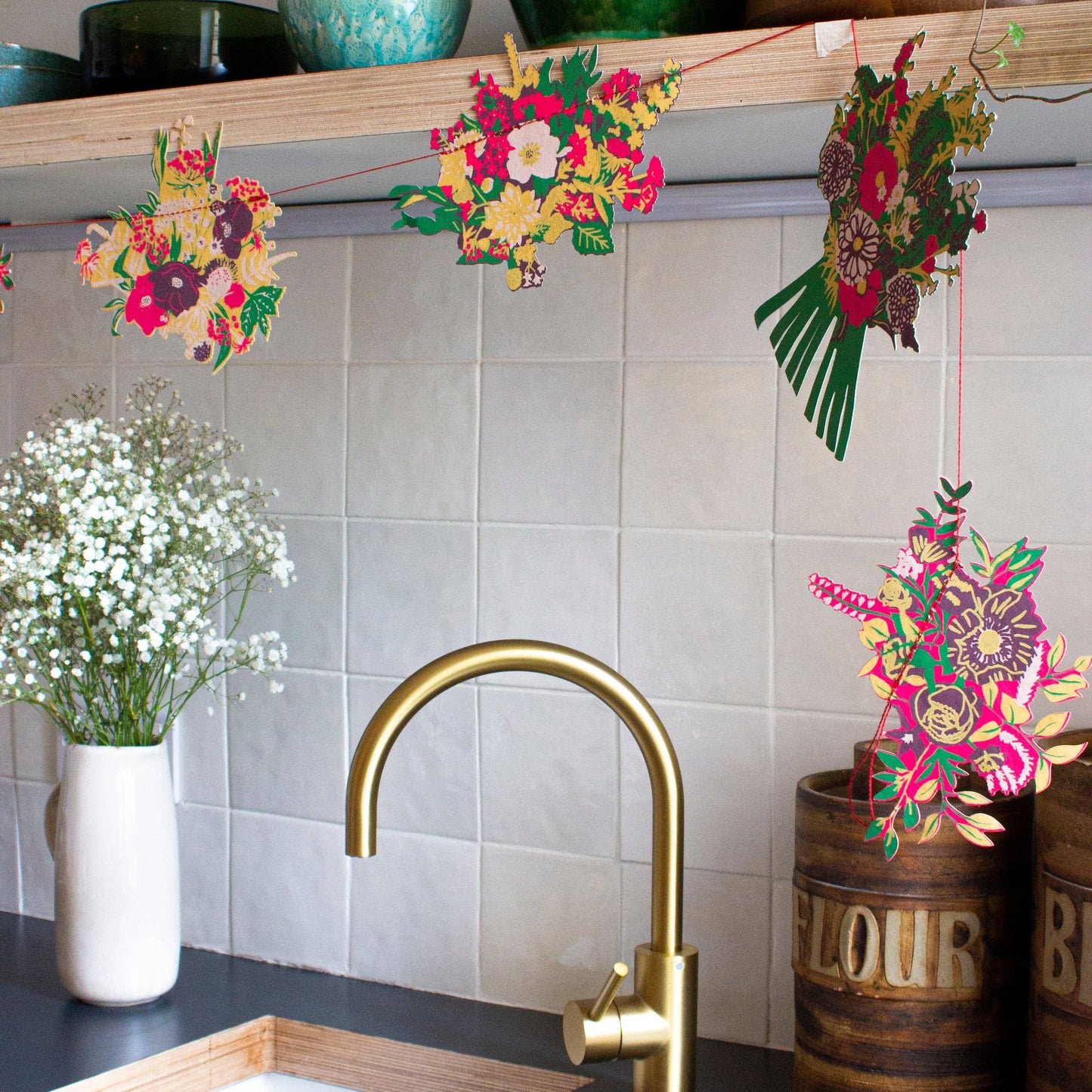 Decorative floral strings hanging above a kitchen sink with a gold faucet.