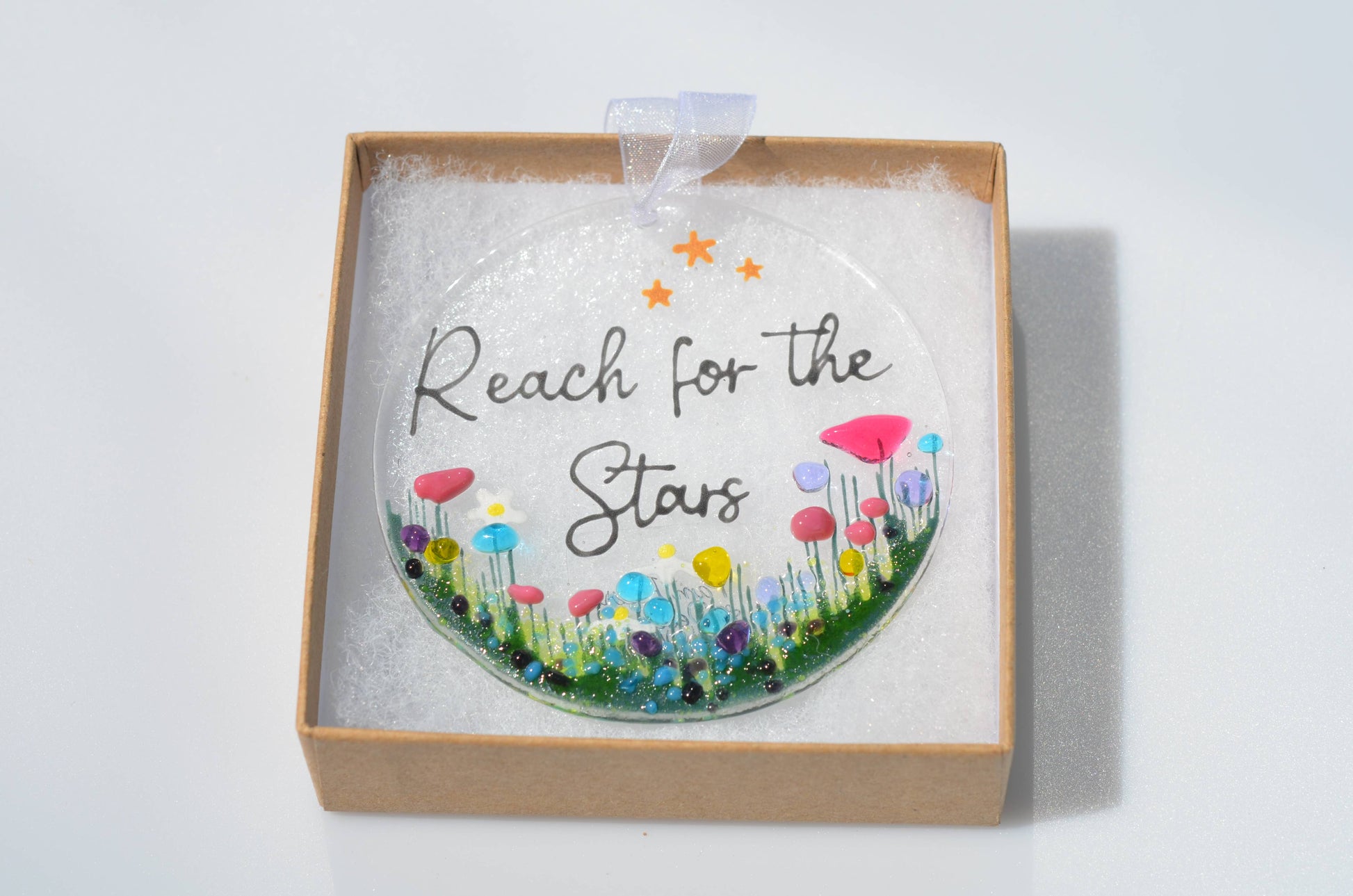 Decorative hanging with 'Reach for the Stars' text and colorful flowers in a box on a white background