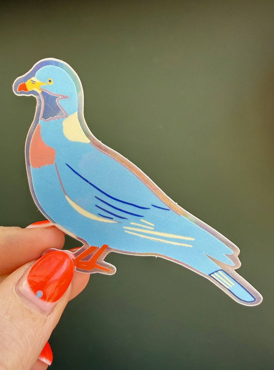 Colorful pigeon-shaped sticker held by a hand with red nail polish against a dark background