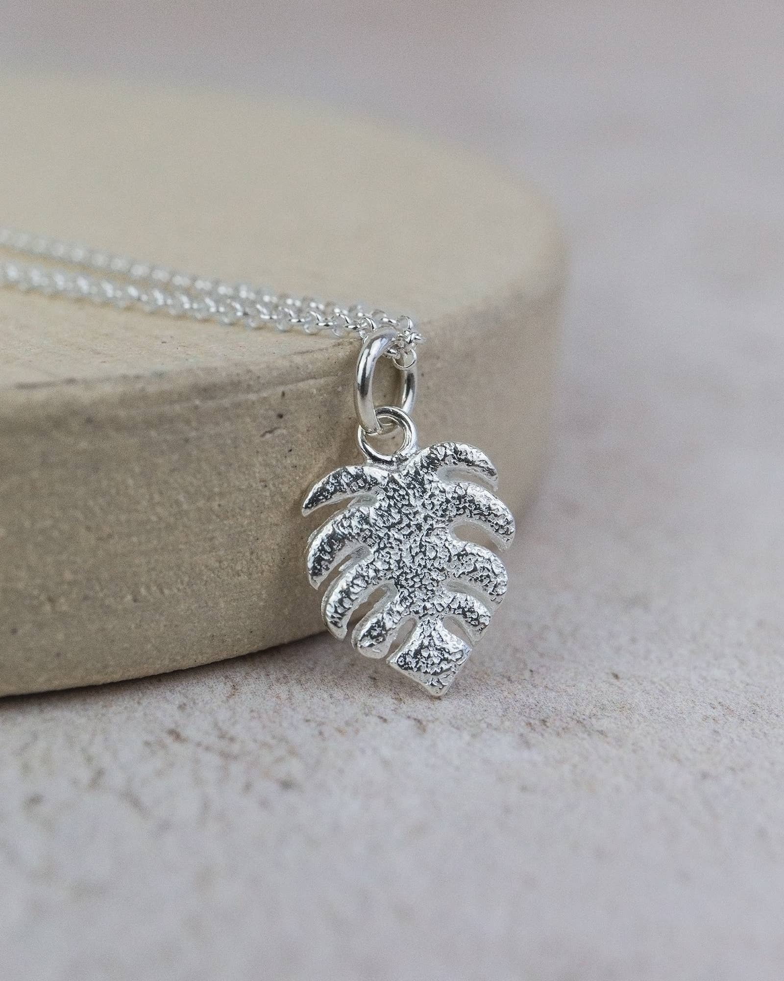 Silver leaf pendant necklace on a light wooden block