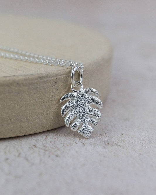 Silver leaf pendant necklace on a light wooden block