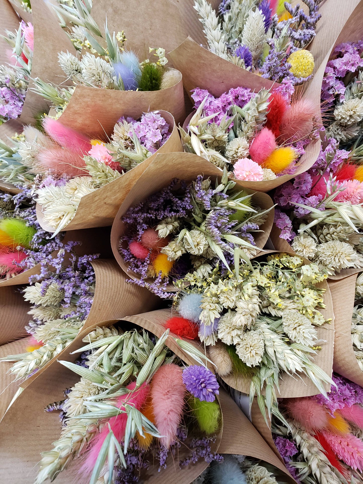 Bouquets of flowers wrapped in brown paper with colorful accents.