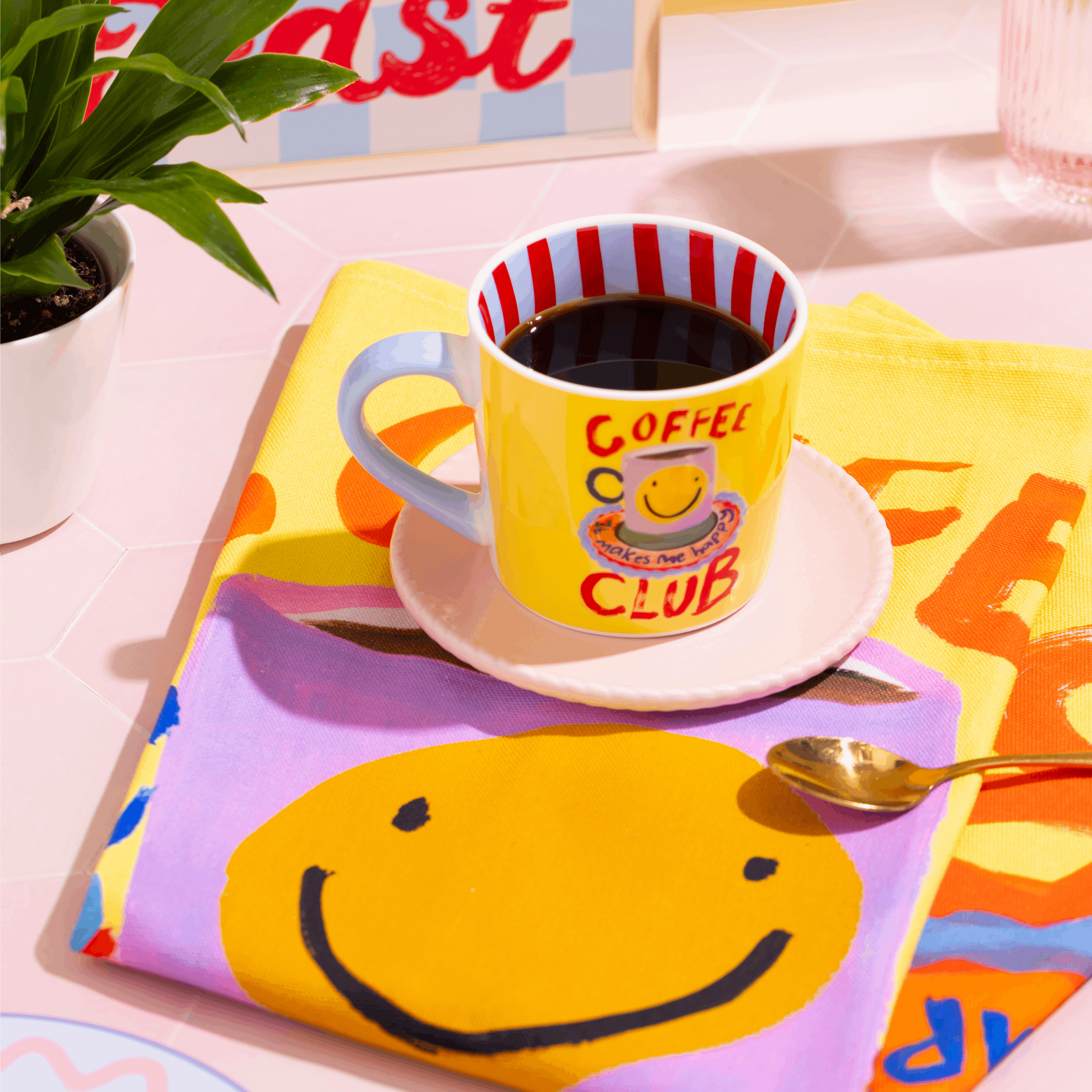 Yellow mug with 'Coffee Club' text on a colorful tablecloth