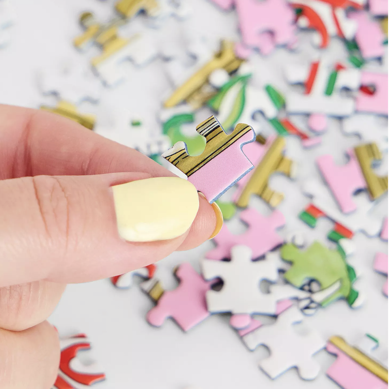 Colorful puzzle pieces with a hand holding a small puzzle piece in front.
