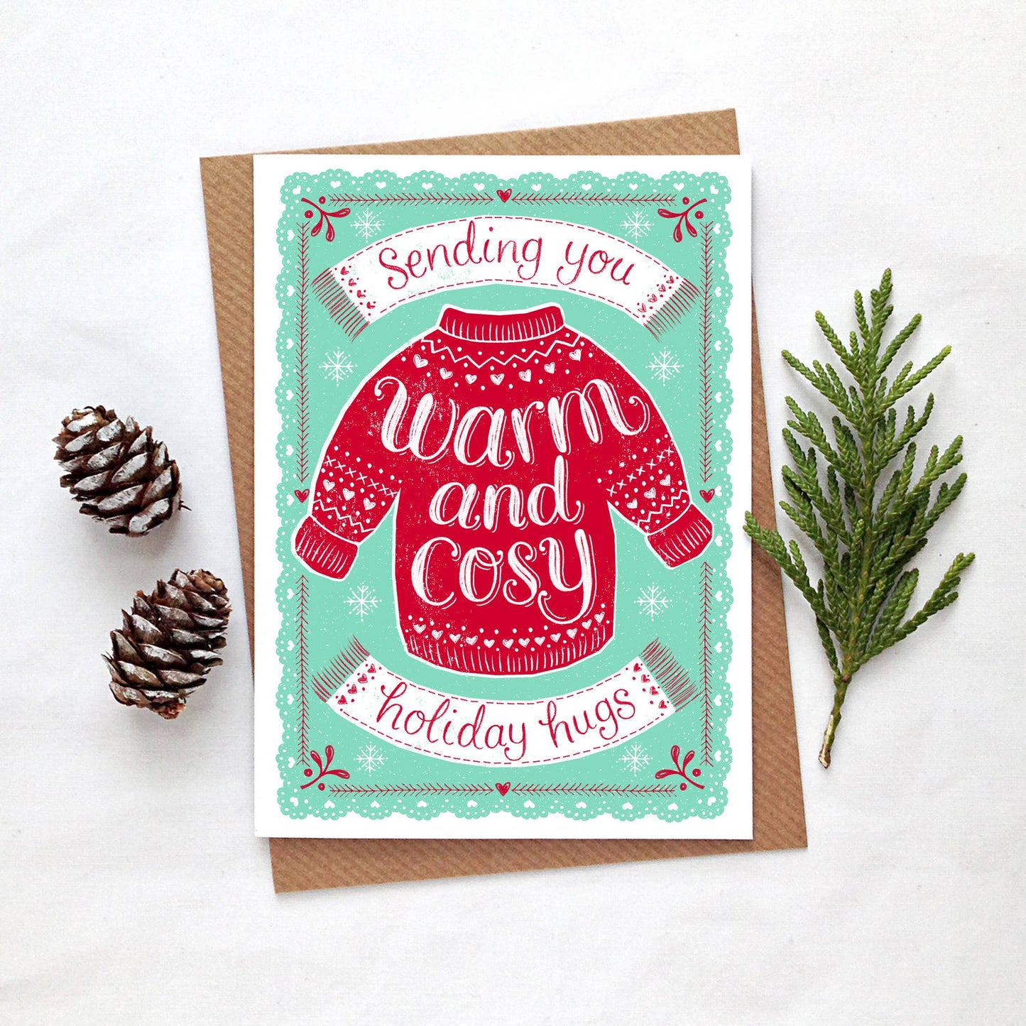 Christmas Card. Illustration with a cosy jumper and texts reads Sending you Warm and cosy holiday hugs.