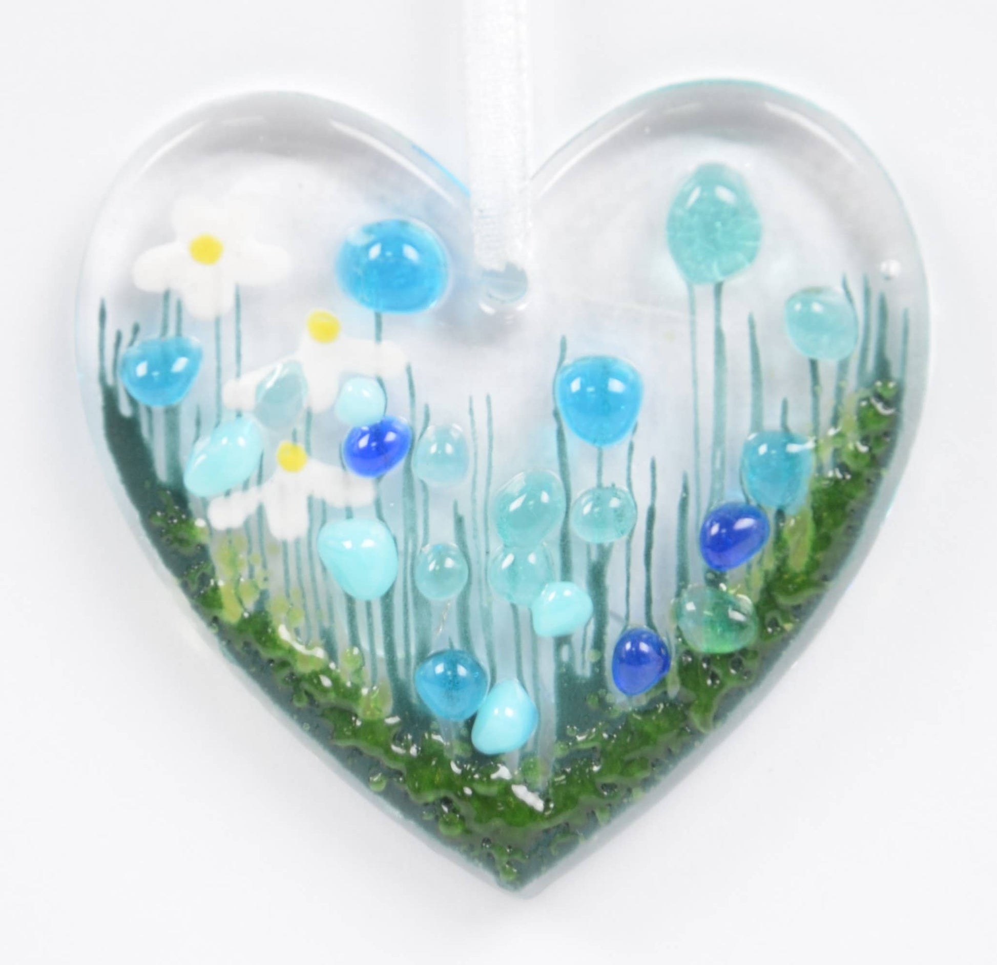 Heart-shaped glass sculpture with blue and green floral design on a white background