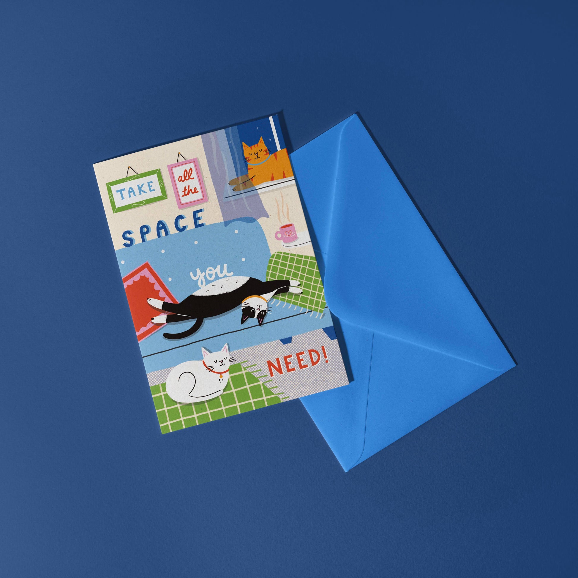 Greeting card with cat illustrations and a blue envelope on a dark blue background