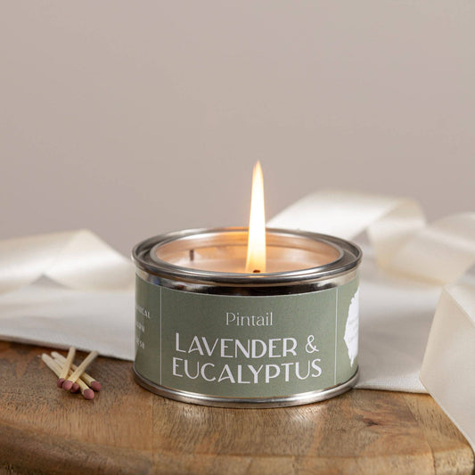 Candle in a tin labeled 'Lavender & Eucalyptus' by Pintail, with matches on a wooden surface.