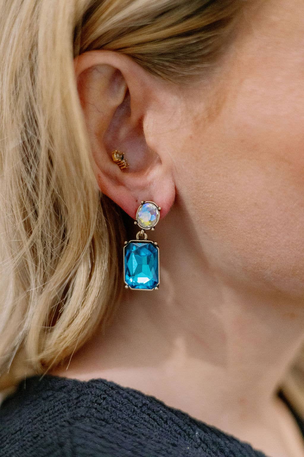 Close-up of a person wearing a blue gemstone earring.