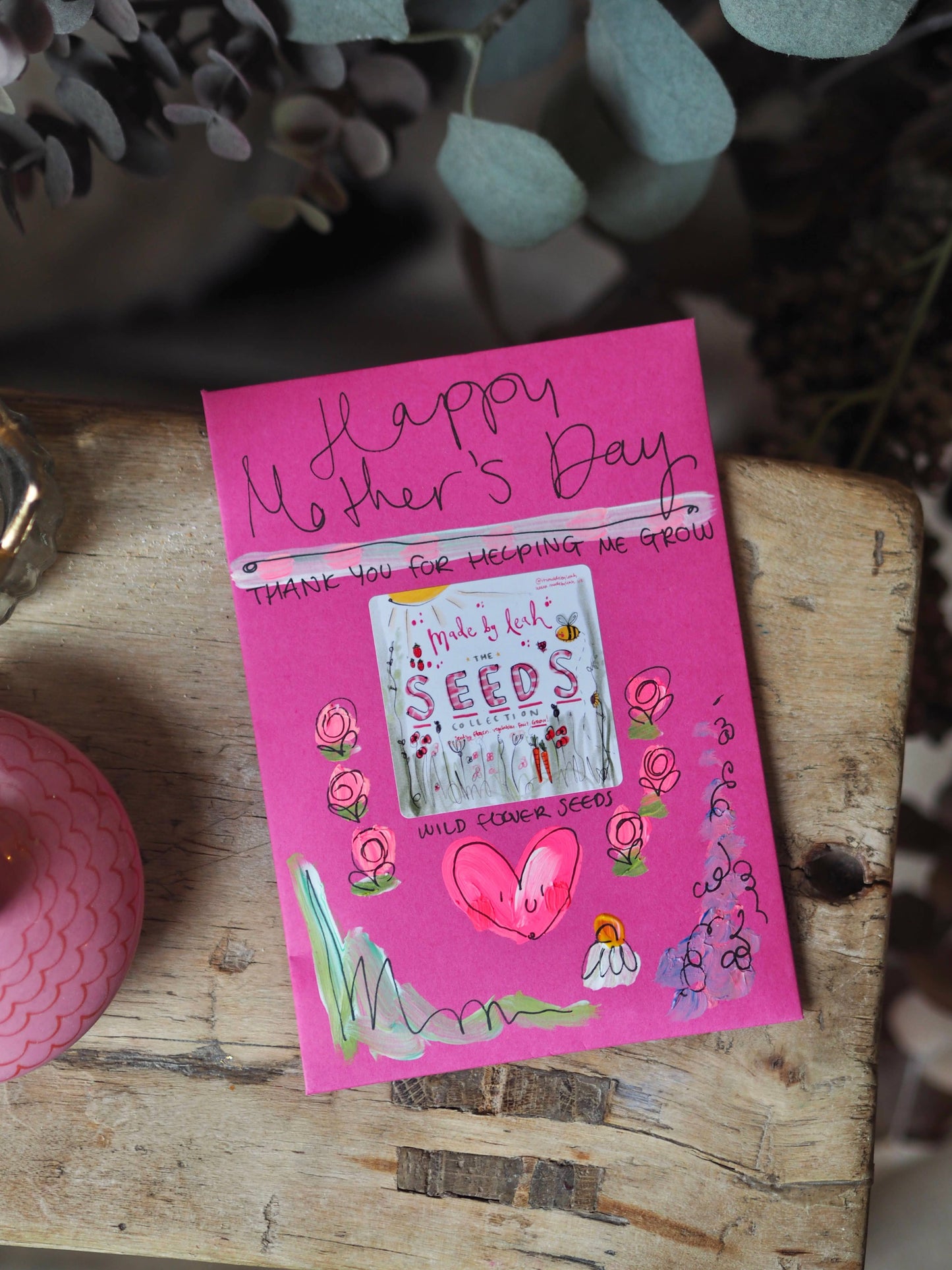 Pink Mother's Day card with illustrations on a wooden surface