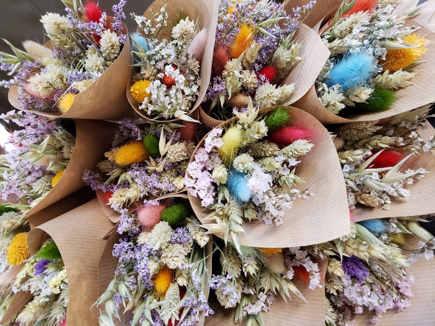 Bouquets of dried flowers in brown paper packaging on a wooden surface