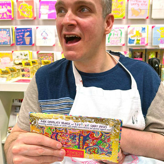 Man holding a colorful chocolate bar with a store in the background