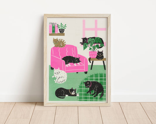 Framed artwork of cats in a living room setting on a white wall.