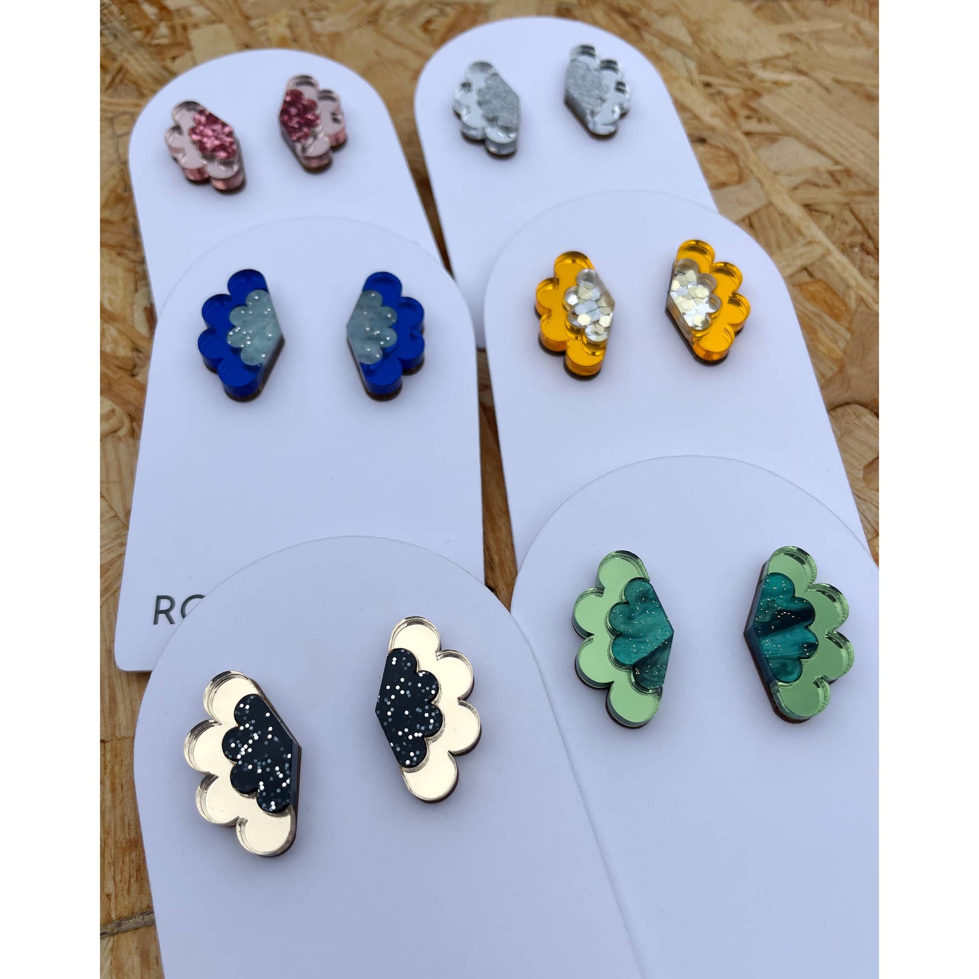Set of colorful earrings on display cards with a wooden background