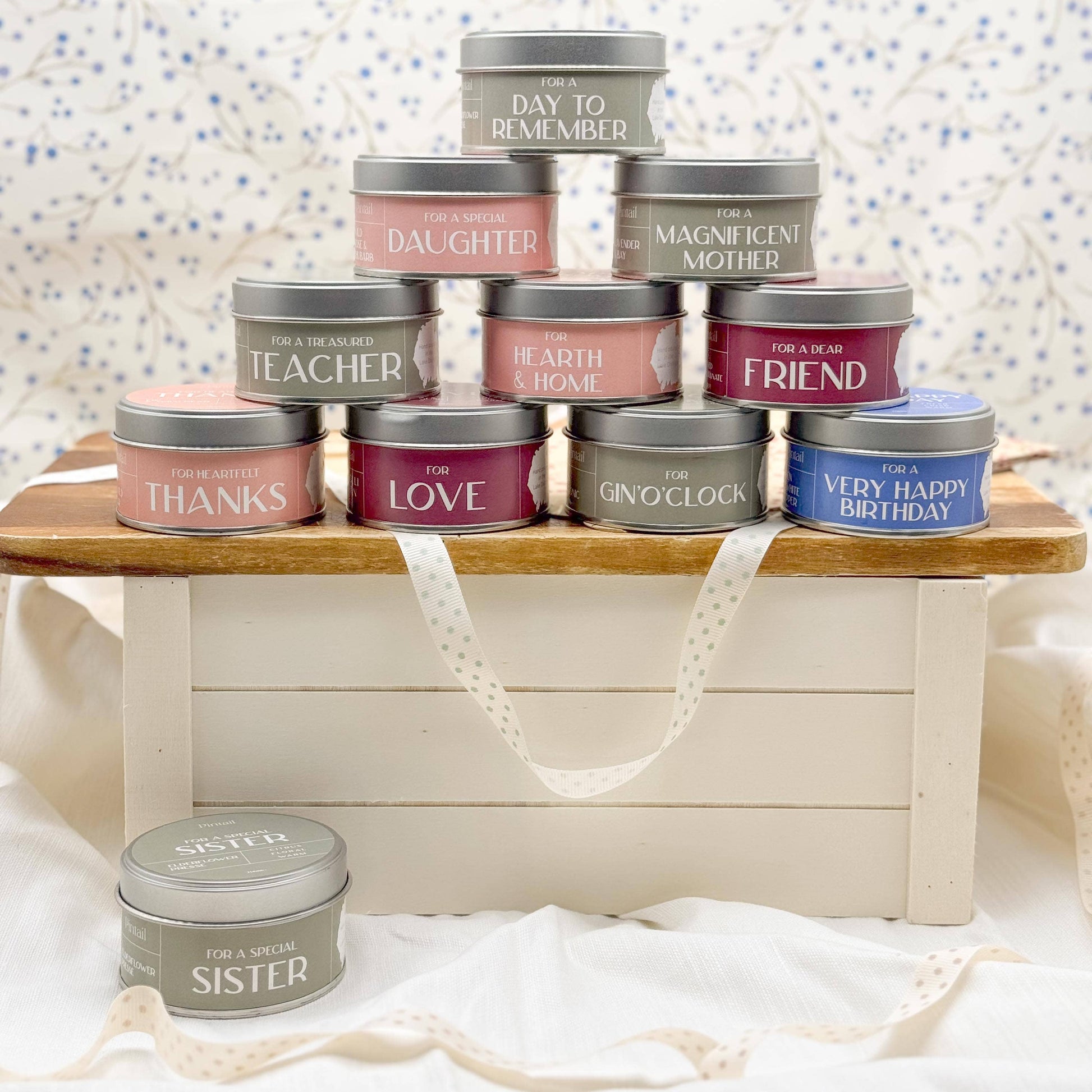 Collection of small tin containers with various sentiments on a wooden stand.