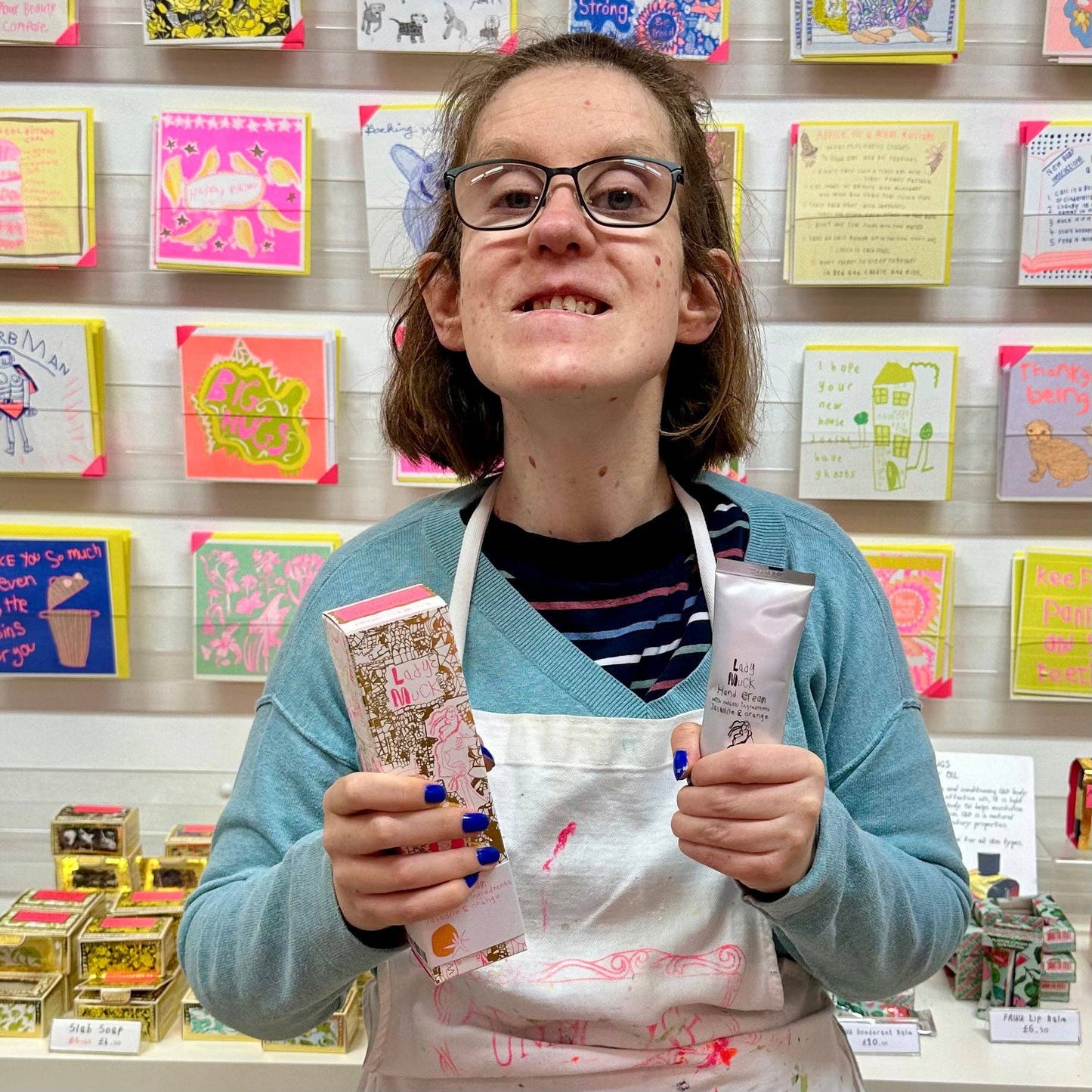 Person holding products in front of a display of colorful cards and boxes.