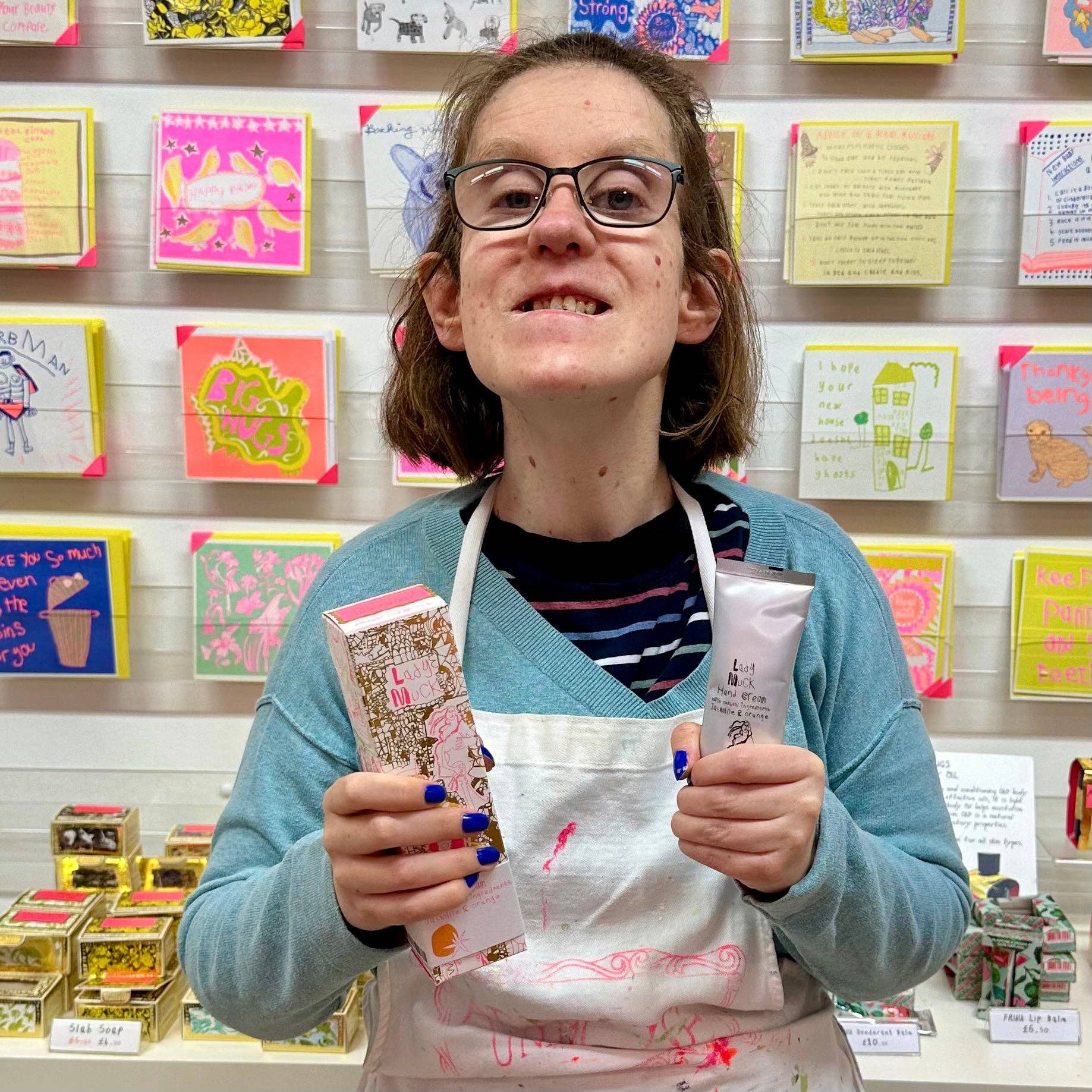 Person holding products in front of a display of colorful cards and boxes.