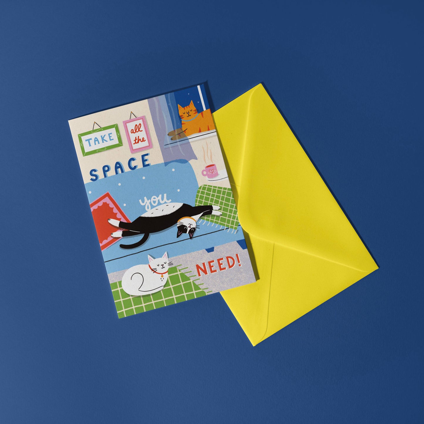 Cats lounging card on a blue background and yellow envelope.