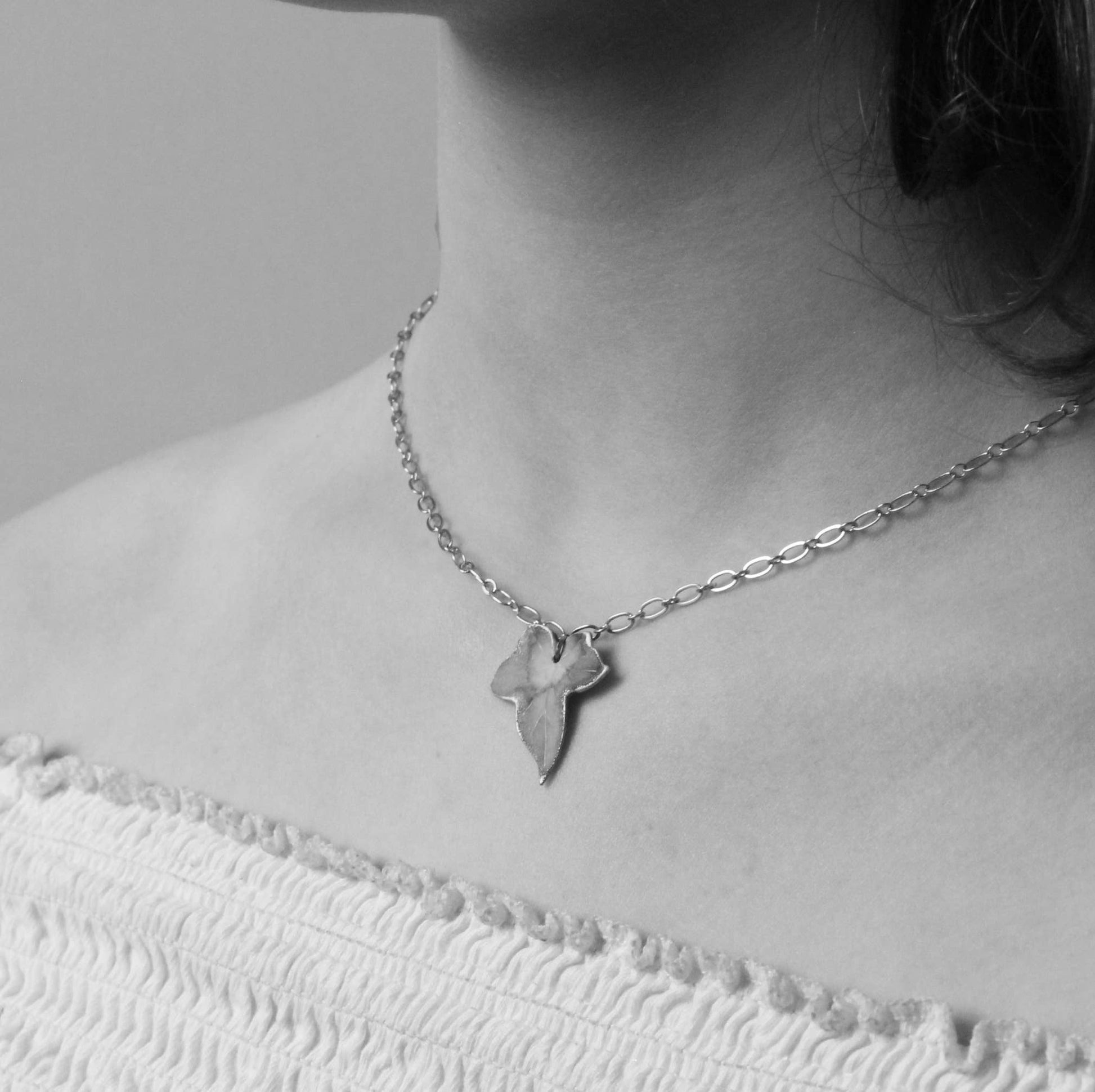 Silver necklace with a pendant worn by a person on a plain background