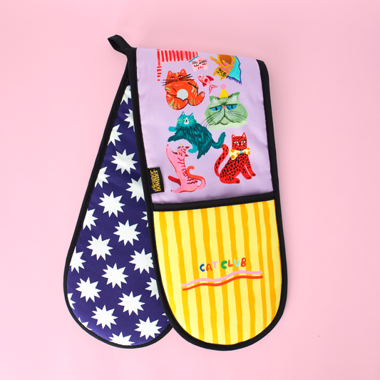 Colorful oven mitt with star pattern, cartoon cats design, and yellow striped pattern on a pink background.