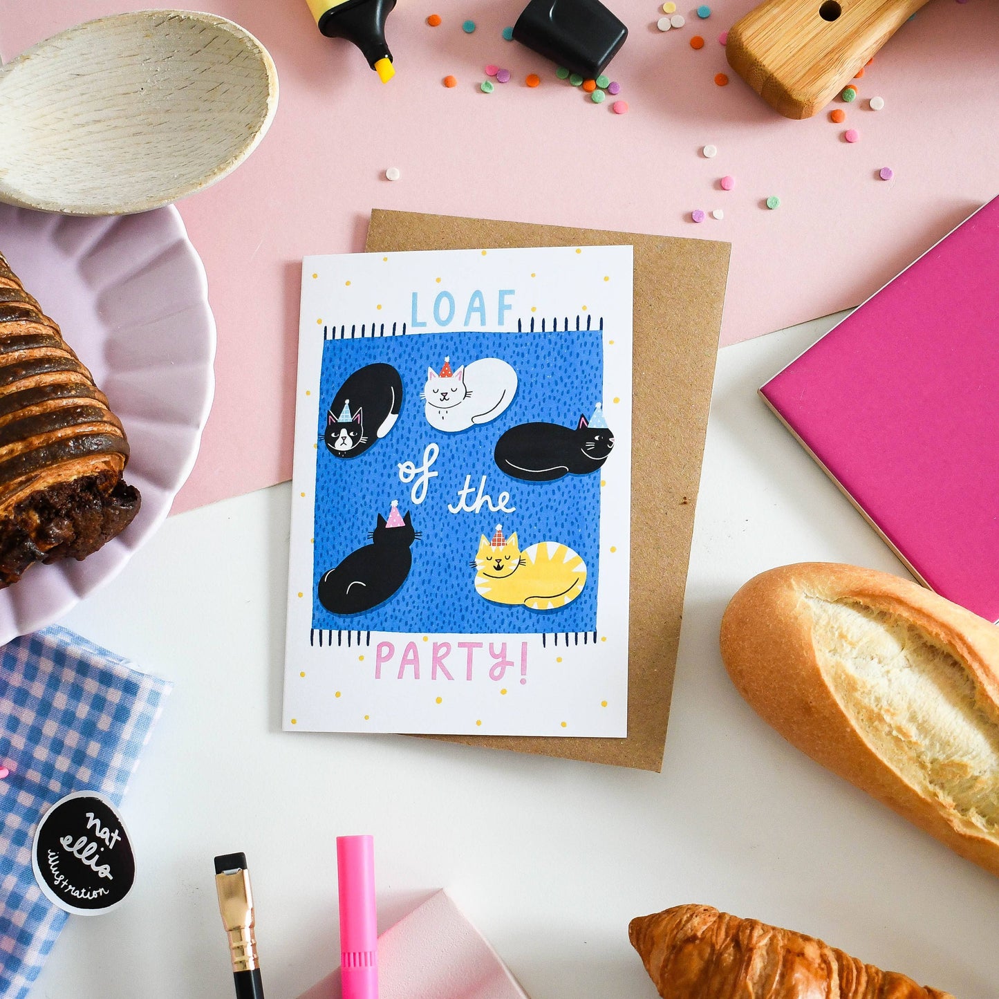 Greeting card with cats and text 'Loaf of the Party!' on a table with bread and other items.